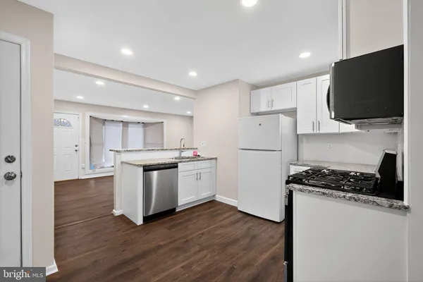 a kitchen with stainless steel appliances white cabinets a stove top oven a sink and a refrigerator