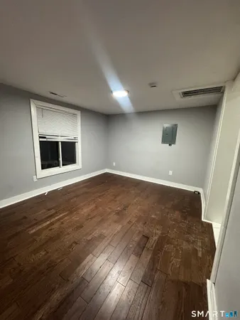 an empty room with wooden floor and windows