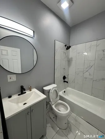 a bathroom with a toilet a sink a mirror and bathtub