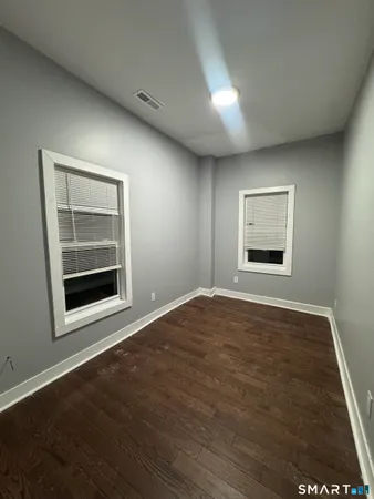 a view of an empty room with a window and wooden floor