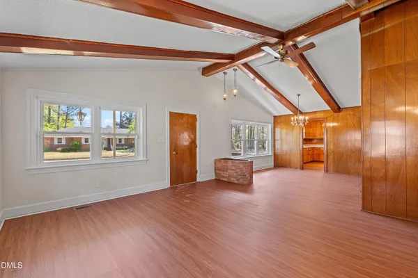 a view of an empty room with a window and wooden floor