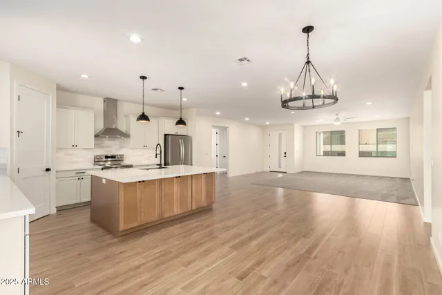 a large kitchen with stainless steel appliances granite countertop a sink a stove and a wooden floors