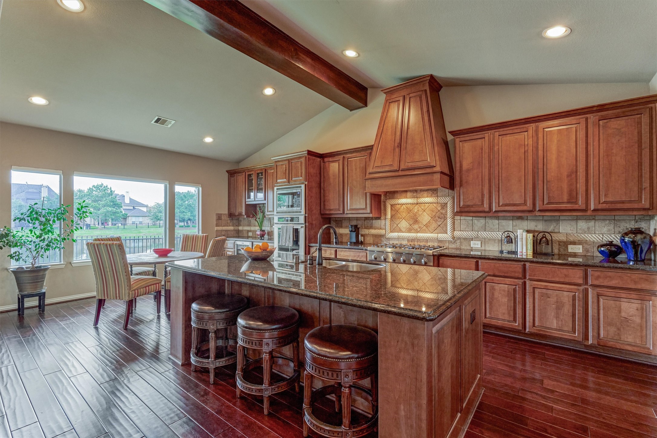 82 East Crystal Canyon Circle The Woodlands, TX 77389 - Photo 11 of 50 The gourmet kitchen boasts a large butcher-block island with bar seating, granite countertops, and abundant cabinetry and prep space throughout.
