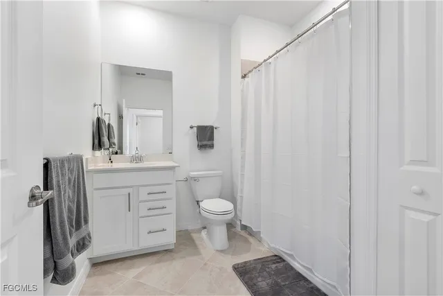 a bathroom with a sink a toilet a mirror and shower curtain
