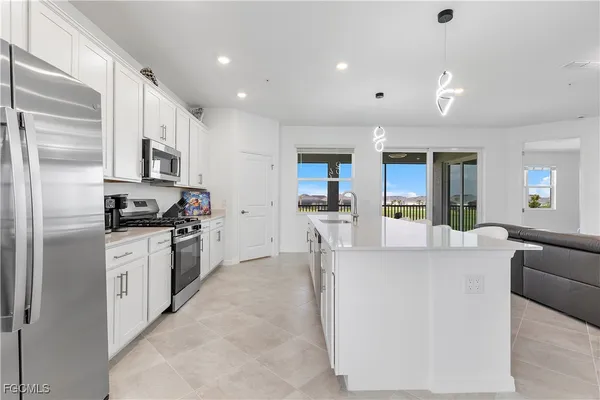 a kitchen with stainless steel appliances granite countertop a refrigerator oven a sink dishwasher and white cabinets with wooden floor