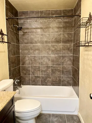 a bathroom with a granite countertop bathtub toilet and sink