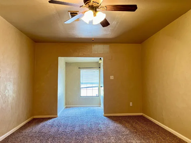 an empty room with closet and a chandelier fan