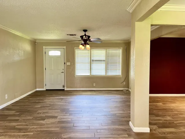 a view of an empty room with window and wooden floor