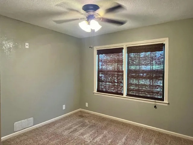 an empty room with a window and a fan