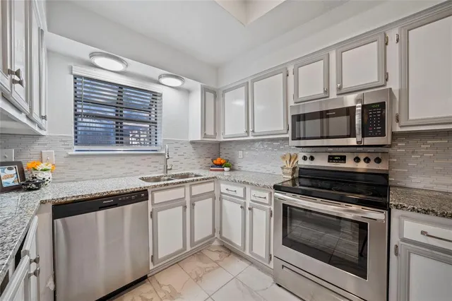 a kitchen with granite countertop a stove sink and microwave