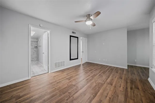 a view of empty room with wooden floor and fan