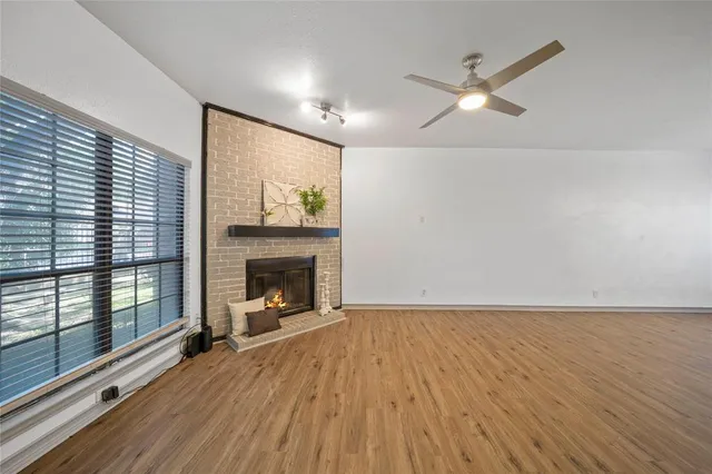 a view of an empty room with wooden floor fireplace and a window