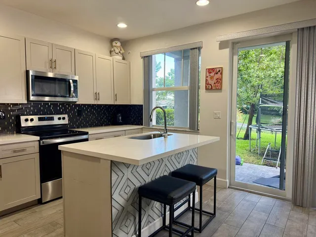 a kitchen with stainless steel appliances granite countertop a stove a sink a microwave a refrigerator and cabinets