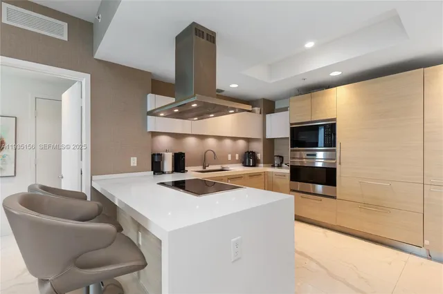 a kitchen with stainless steel appliances kitchen island granite countertop a sink a stove and chairs