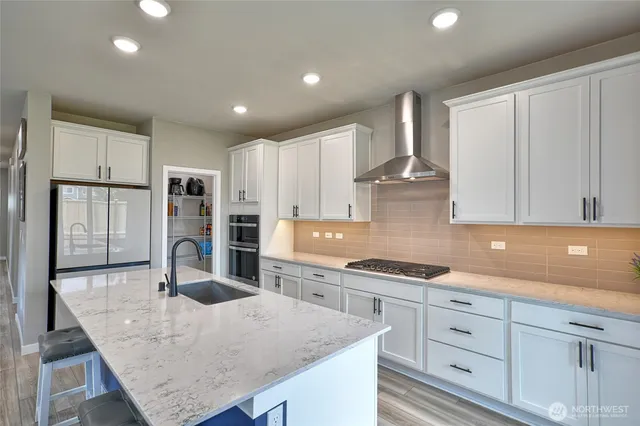 a kitchen with stainless steel appliances granite countertop a sink a stove and white cabinets
