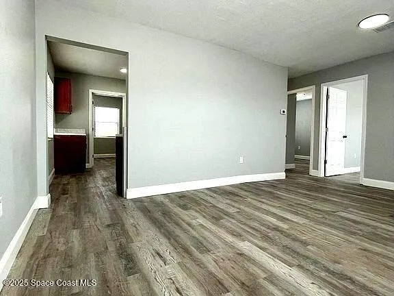 an empty room with wooden floor and entrance