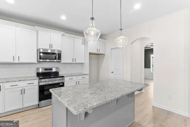 a kitchen with granite countertop white cabinets and stainless steel appliances