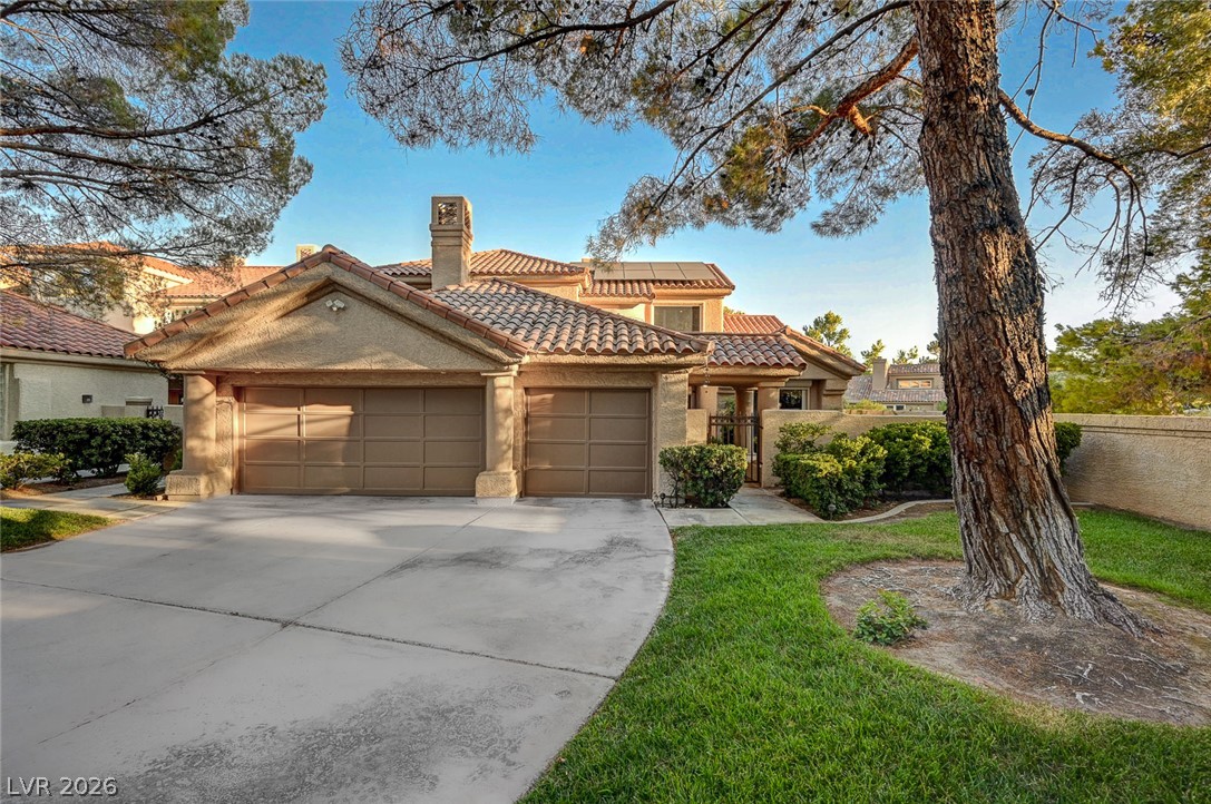7995 Rio Rico Drive Las Vegas, NV 89113 - Photo 1 of 92 Two-car garage home featuring a clay tile roof and lush green landscaping.