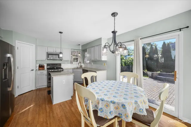 a kitchen with kitchen island a dining table chairs stainless steel appliances and cabinets
