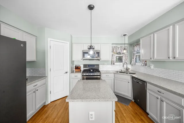 a kitchen with kitchen island a counter top space appliances and cabinets