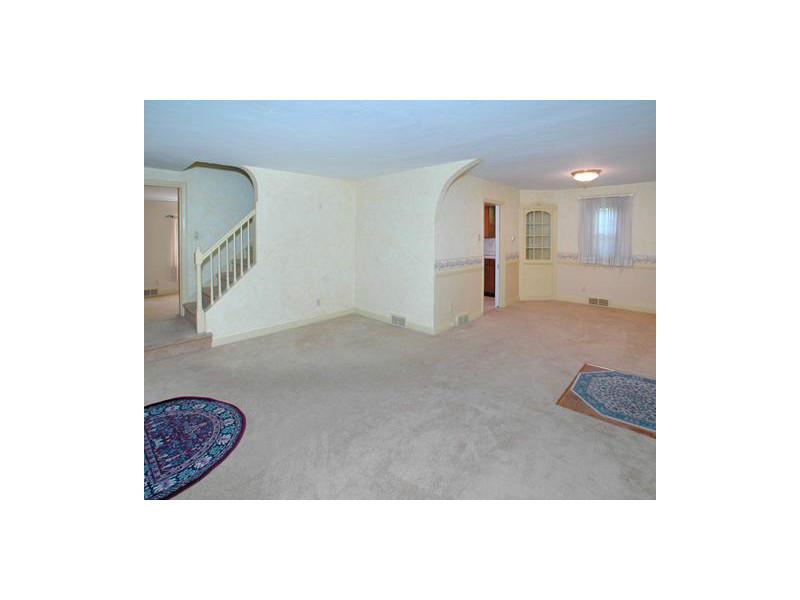 Living Room. This view of the living room is taken from the front corner looking into the dining room and kitchen, shows the stairway to the second floor, and on the far left you can see the first-floor family room.