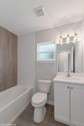 a bathroom with a toilet a sink a mirror a bathtub and vanity