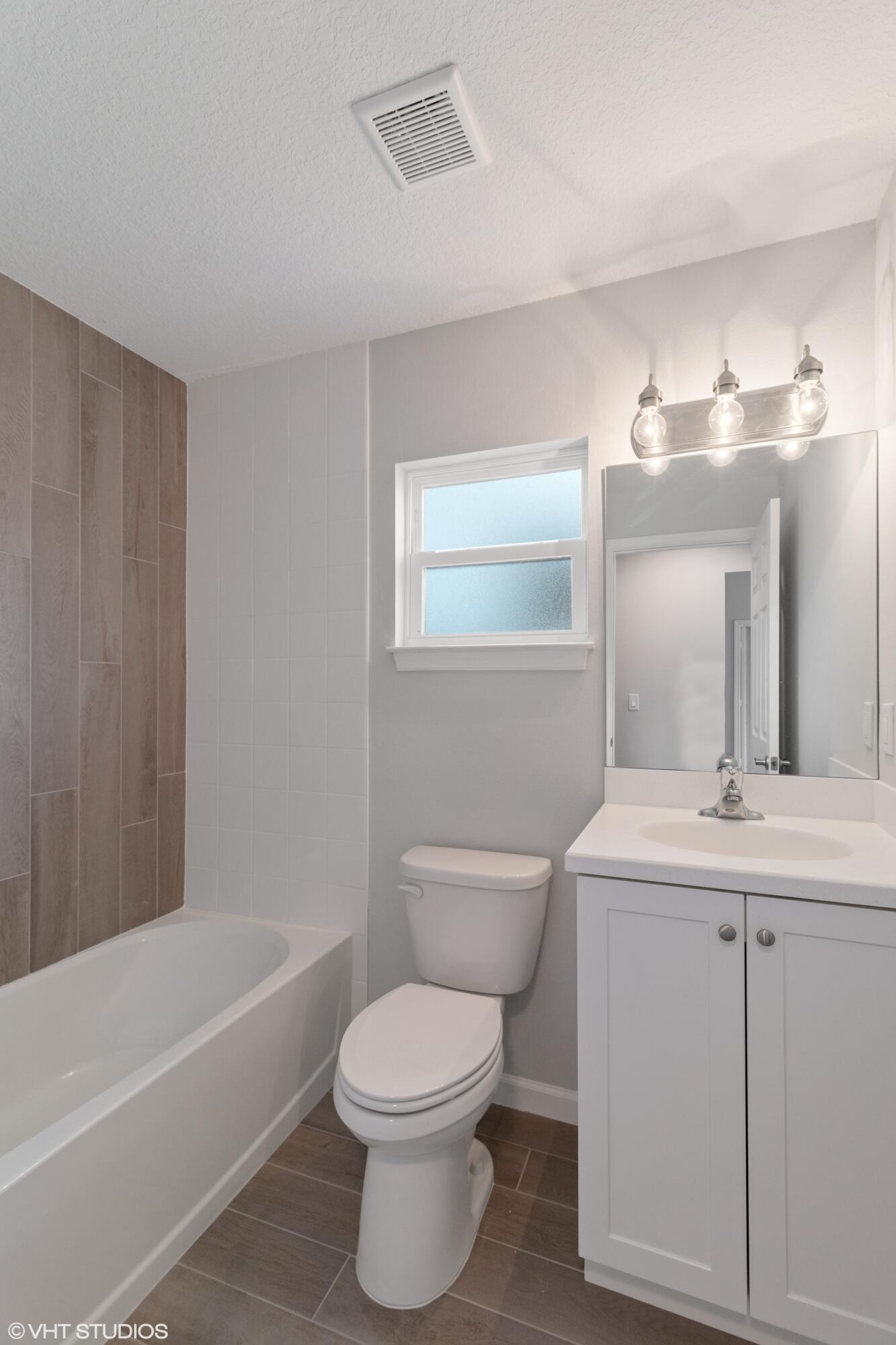 4910 Southeast Jack Avenue Stuart, FL 34997 - Photo 13 of 14 a bathroom with a toilet a sink a mirror a bathtub and vanity