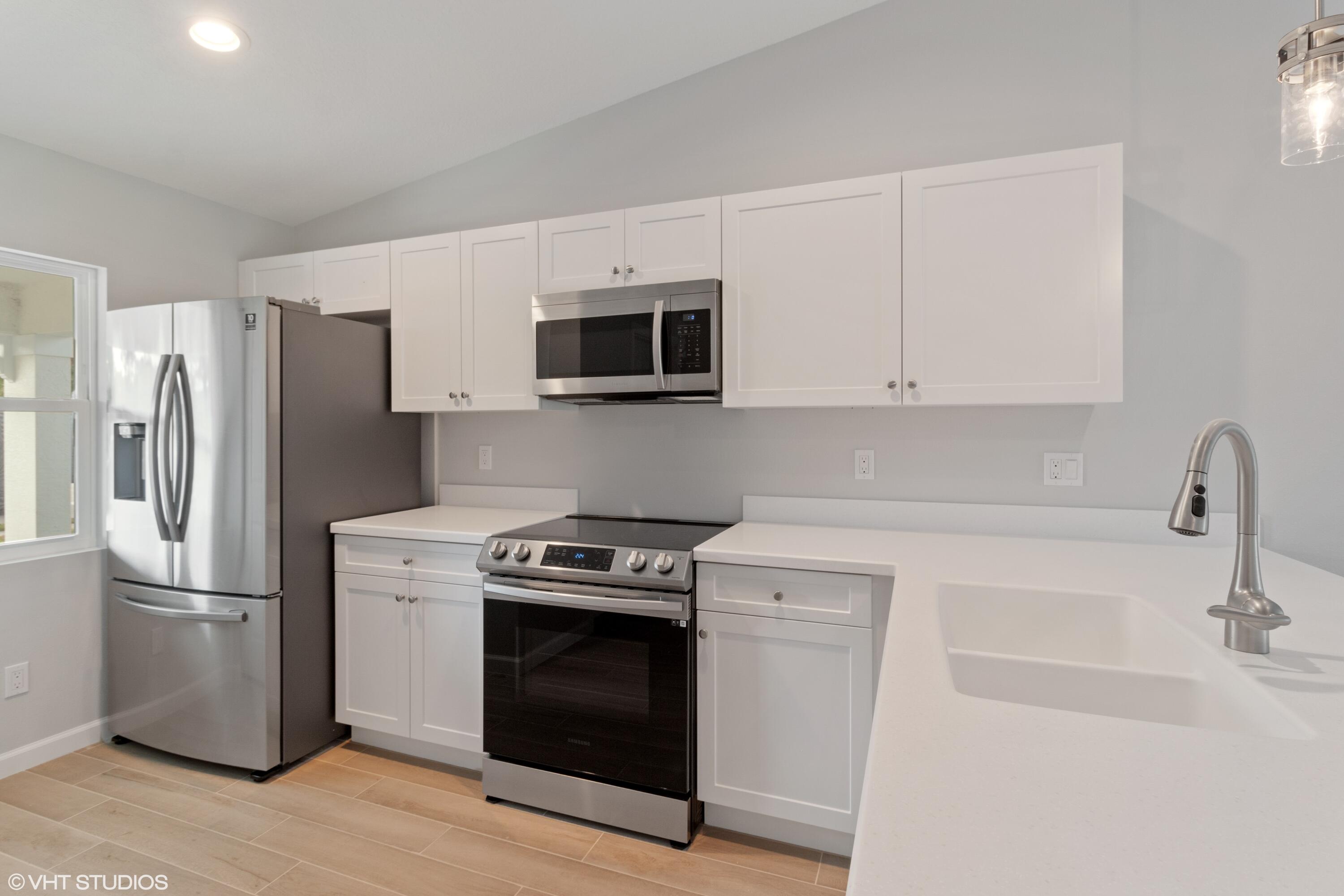 4910 Southeast Jack Avenue Stuart, FL 34997 - Photo 5 of 14 a kitchen with stainless steel appliances a stove a microwave a sink and cabinets