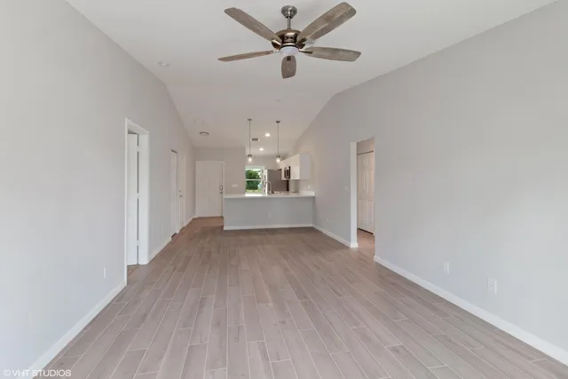 a view of a livingroom with a ceiling fan wooden floor and a ceiling fan