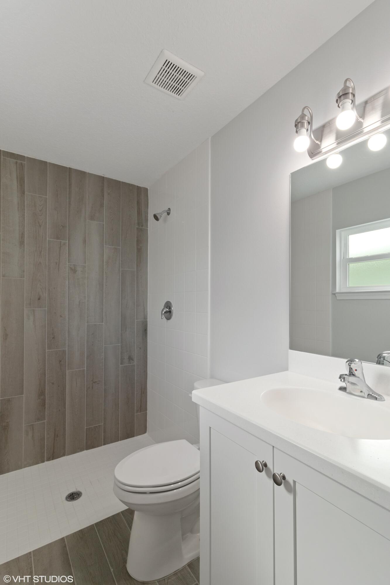 4910 Southeast Jack Avenue Stuart, FL 34997 - Photo 10 of 14 a bathroom with a sink a toilet and shower