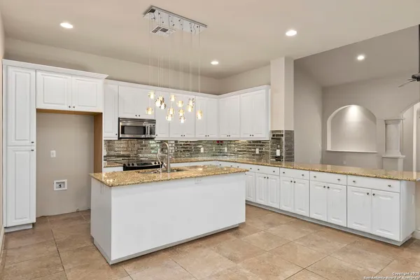 a kitchen with stainless steel appliances granite countertop a sink and dishwasher a stove top oven with white cabinets