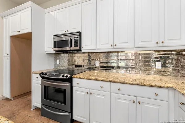 a kitchen with granite countertop white cabinets and stainless steel appliances
