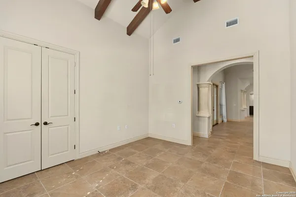 an empty room with chandelier fan and windows