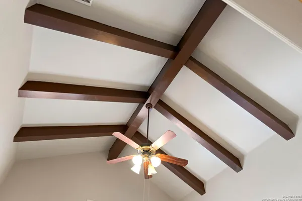 an empty room with wooden floor ceiling fan and windows