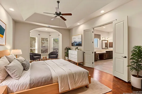 an empty room with wooden floor a ceiling fan and windows