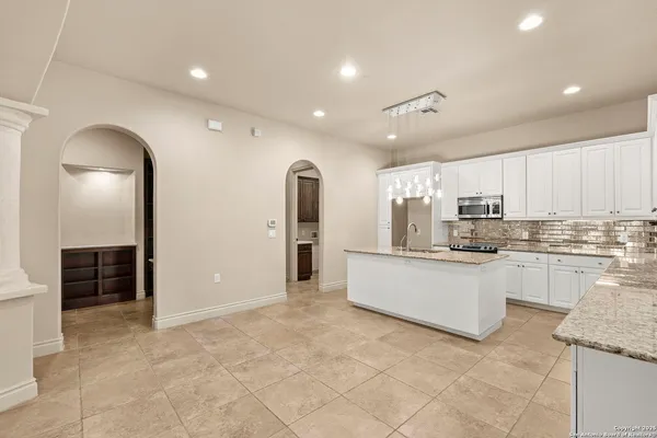 a large white kitchen with kitchen island a sink a stove and a refrigerator