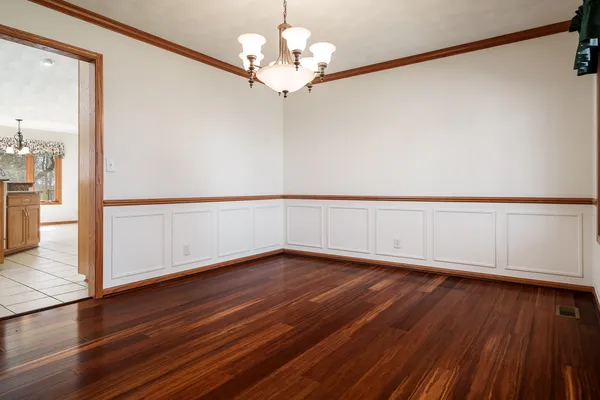 a view of an empty room with window and wooden floor