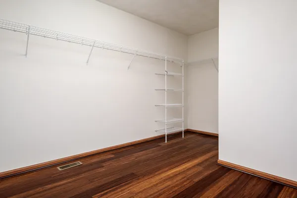 an empty room with wooden floor chandelier fan and windows