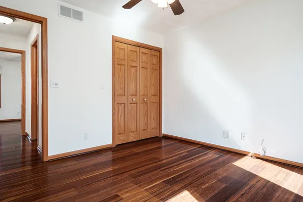 a view of empty room with wooden floor and fan