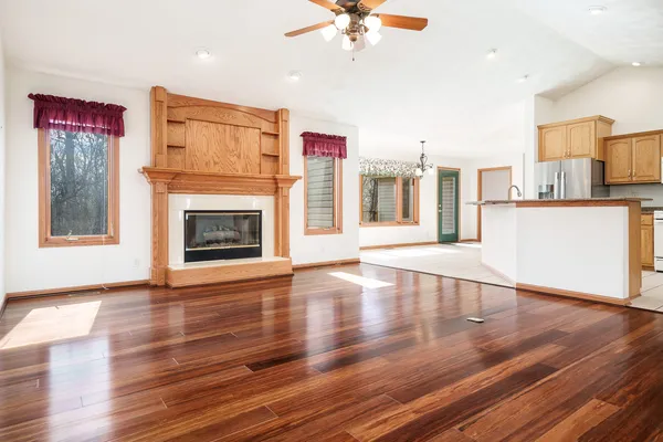 a view of an empty room with wooden floor and a chandelier