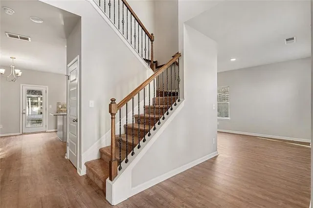 a view of staircase with wooden floor and a chandelier