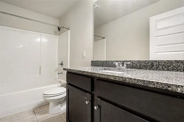 a bathroom with a granite countertop sink a toilet and shower