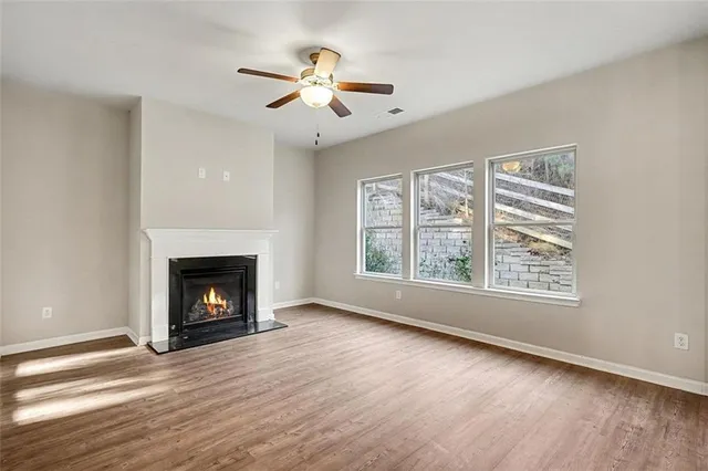 a view of an empty room with wooden floor fireplace and a window
