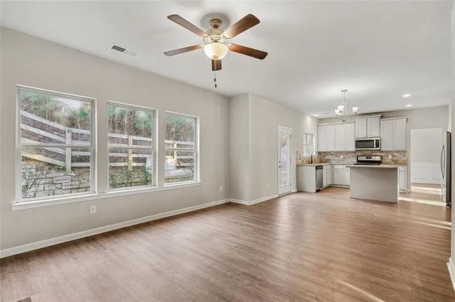 a view of an empty room with window wooden floor and a kitchen
