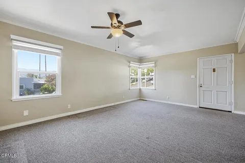 an empty room with windows and fan