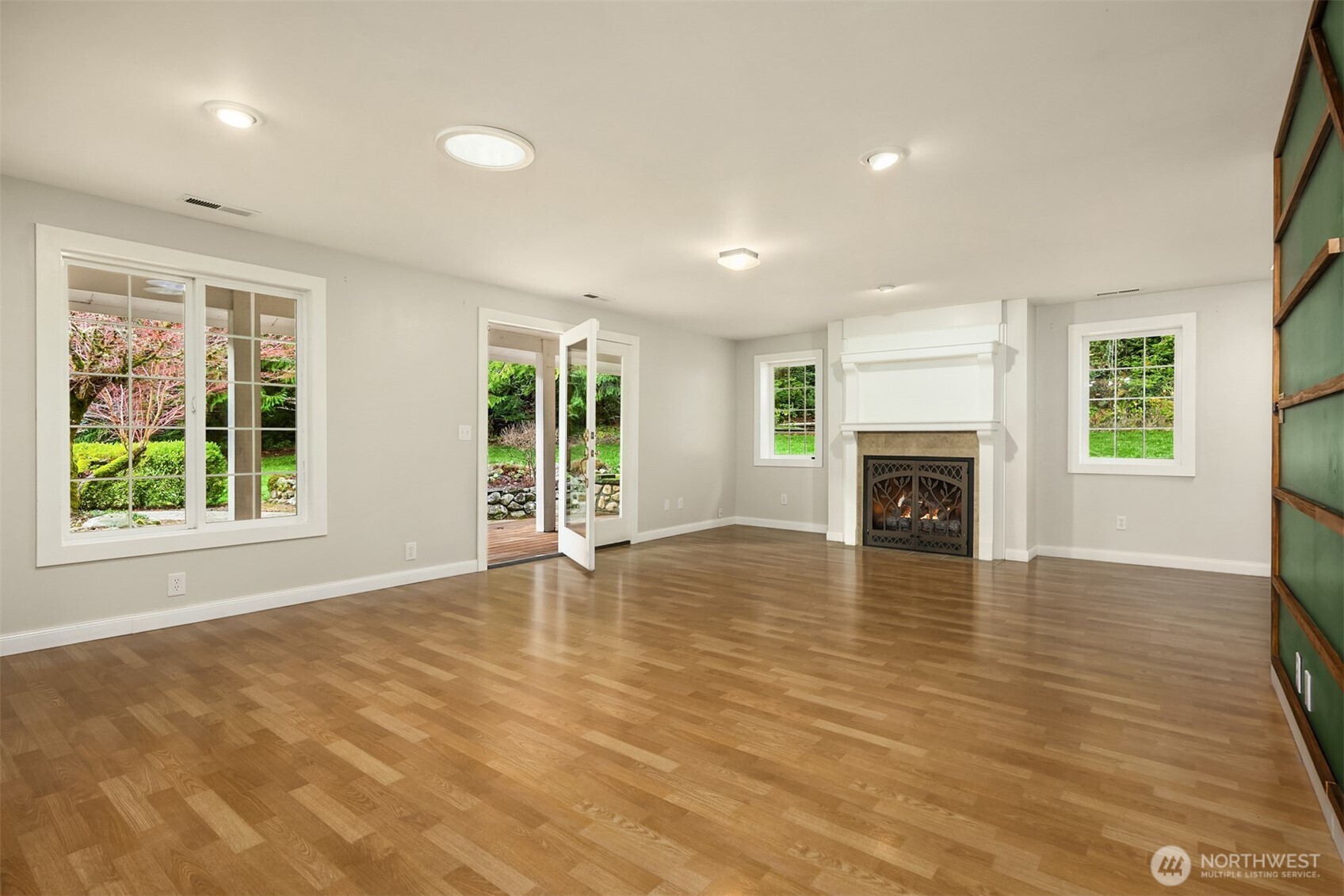 12620 Old Military Road Northeast Poulsbo, WA 98370 - Photo 8 of 35 an empty room with windows fireplace and wooden floor