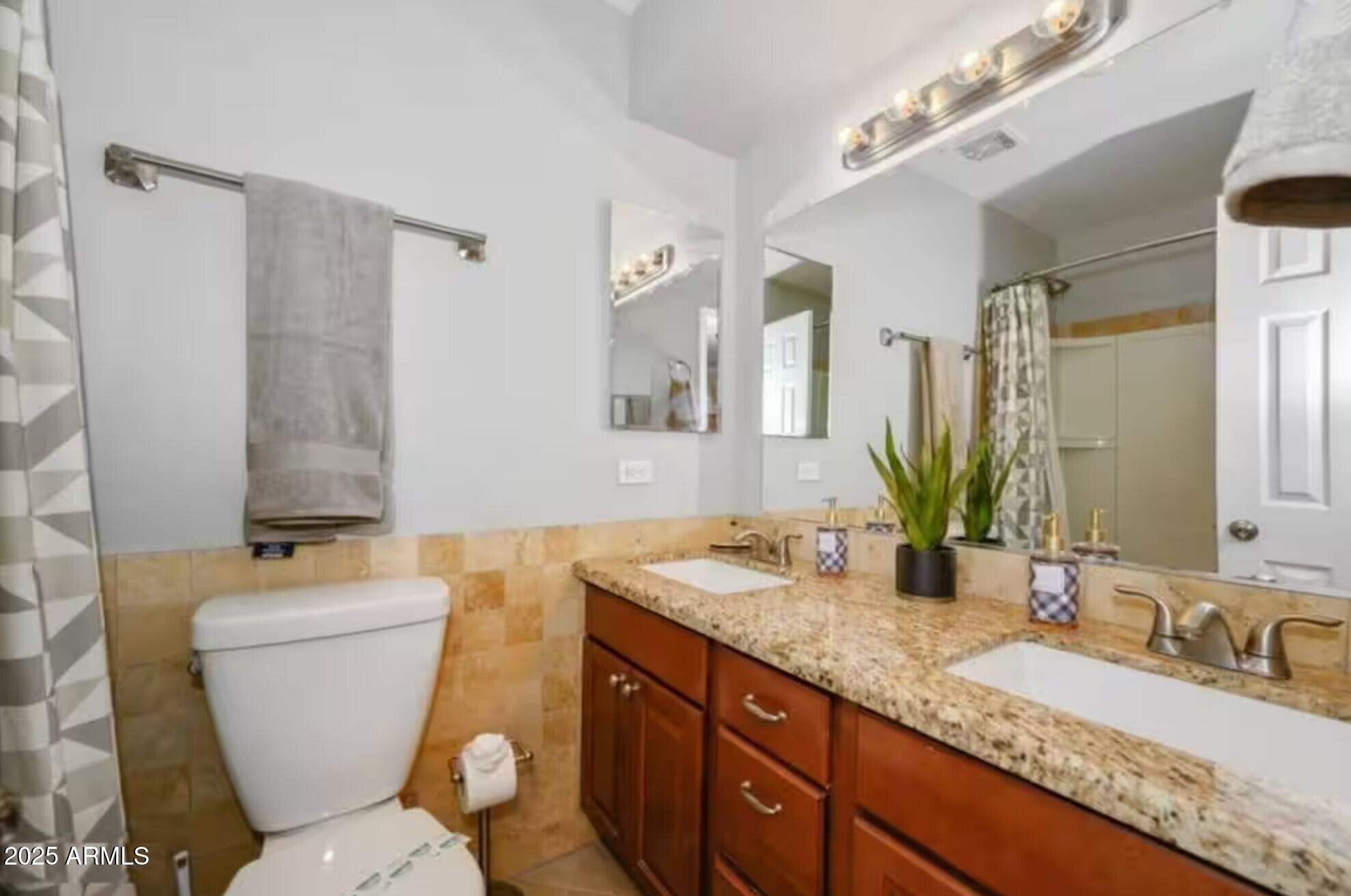 1612 West Geneva Drive Tempe, AZ 85282 - Photo 21 of 36 a bathroom with a granite countertop toilet a sink and a mirror