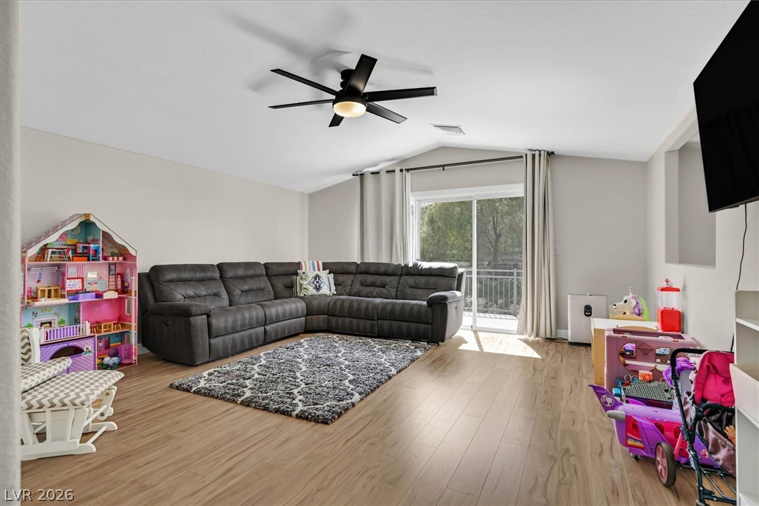 1259 Moon Vision Street Henderson, NV 89052 - Photo 24 of 53 A comfortable living space featuring warm wood flooring and a sliding glass door leading to a private balcony.