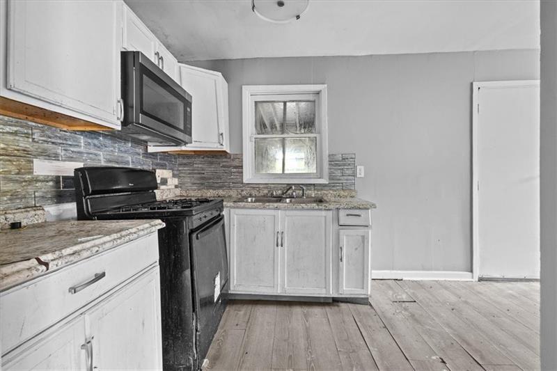 685 Bolton Road Northwest Atlanta, GA 30331 - Photo 6 of 21 a kitchen with stainless steel appliances granite countertop a sink a stove a microwave and wooden floors
