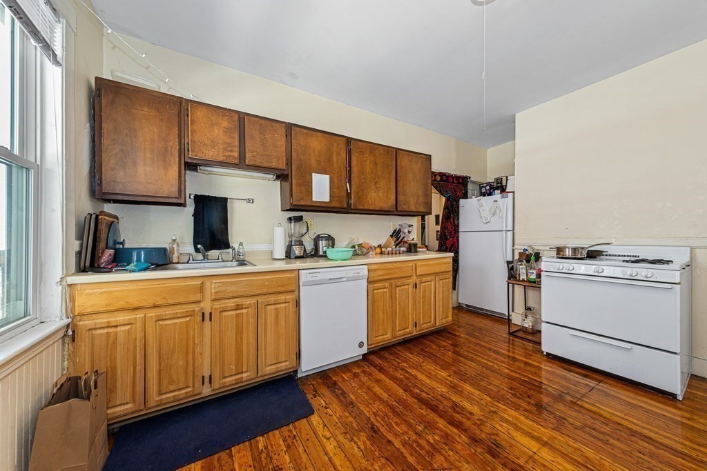87 Parkton Road Boston, MA 02130 - Photo 34 of 42 a kitchen with sink a stove and white cabinets with wooden floor